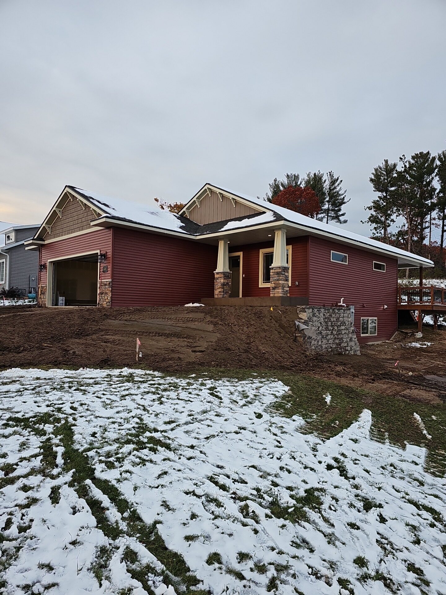 Newly sided red single-story home with stone-column porch and attached garage, light snow on roof and lawn, showcasing durable exterior siding suited for Wisconsin weather